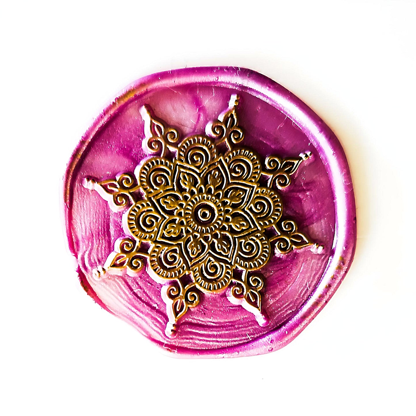 a round wax stamp in pink and gold colors